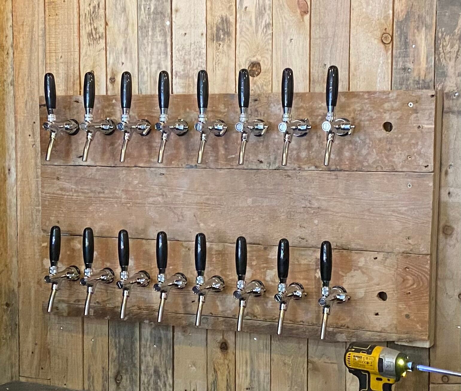 Rows of commercial draught beer taps mounted on a wooden wall